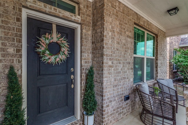 property entrance with a porch and brick siding