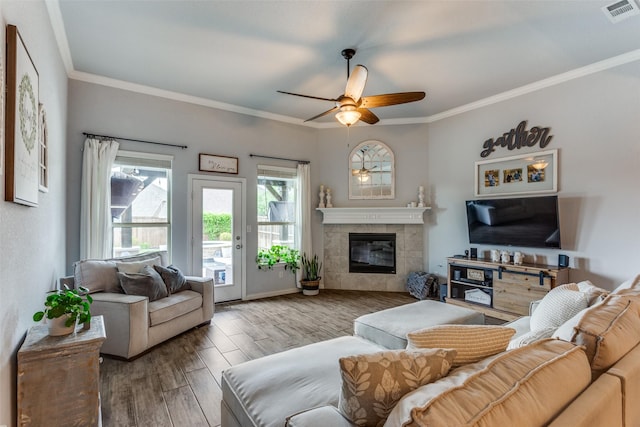 living room with visible vents, crown molding, wood finished floors, a fireplace, and ceiling fan