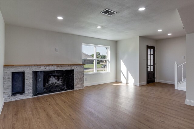 unfurnished living room with a fireplace, recessed lighting, wood finished floors, and visible vents