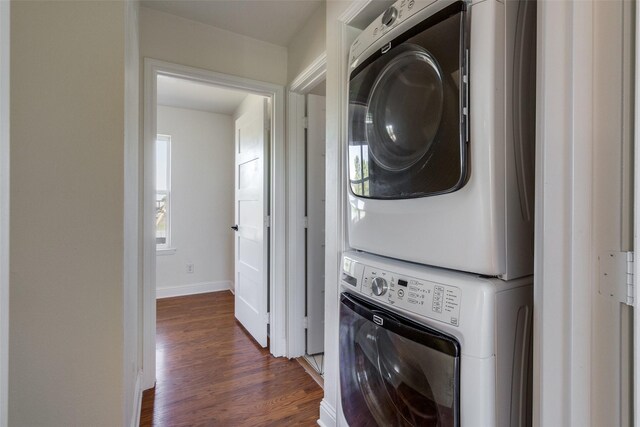 laundry area featuring laundry area, stacked washing maching and dryer, baseboards, and dark wood-type flooring