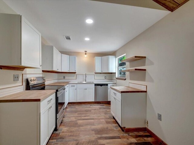 kitchen featuring open shelves, light wood-type flooring, recessed lighting, a sink, and stainless steel appliances