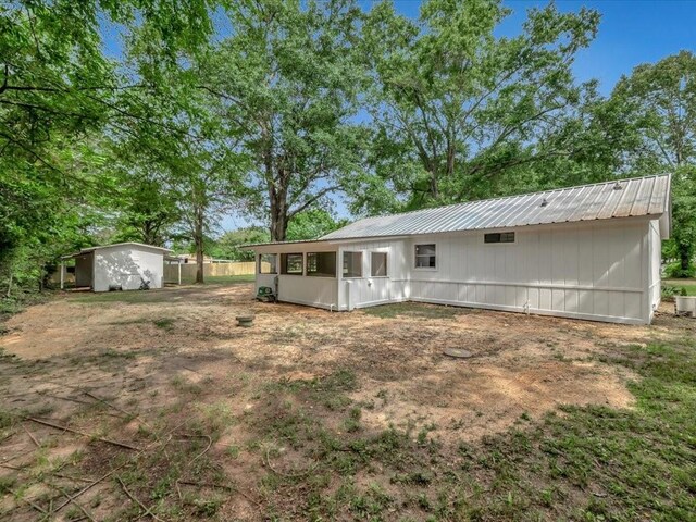 back of house with metal roof and an outdoor structure