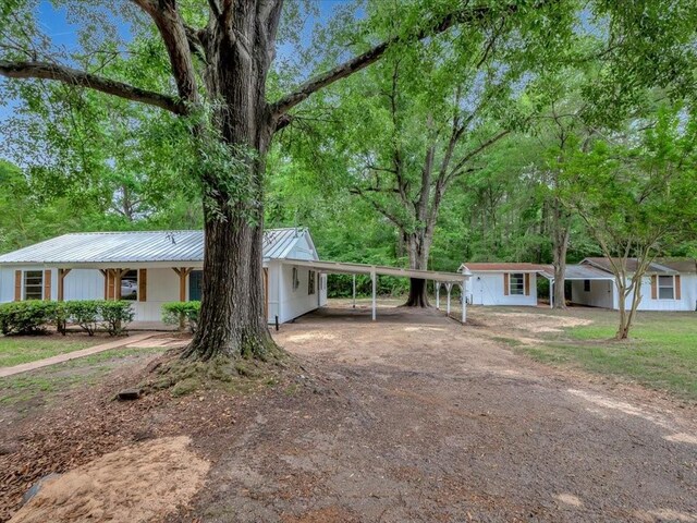 ranch-style house featuring driveway, metal roof, and a carport