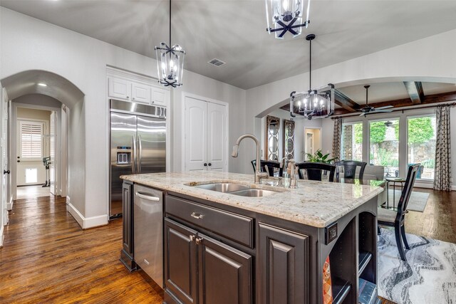 kitchen with stainless steel appliances, arched walkways, dark wood-style floors, and a sink