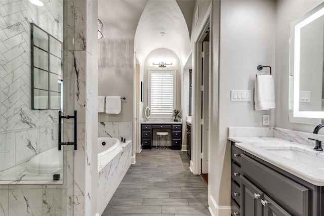 full bathroom with a sink, a bath, and two vanities