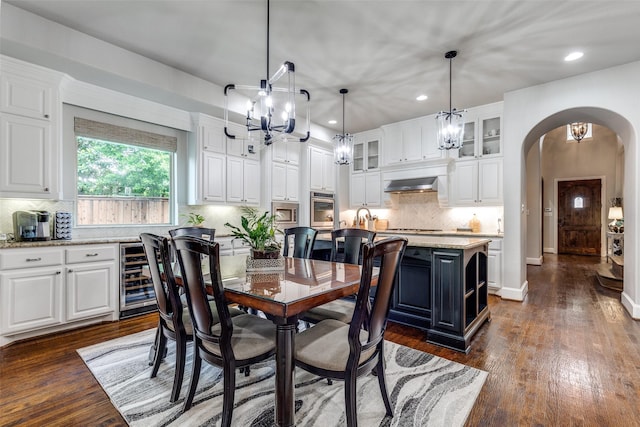 dining area with dark wood-style flooring, beverage cooler, recessed lighting, a chandelier, and arched walkways