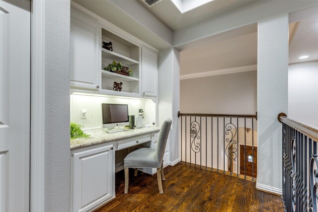 home office featuring built in study area, crown molding, and dark wood-type flooring