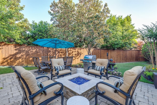 view of patio / terrace with a fenced backyard, outdoor dining area, a fire pit, and area for grilling