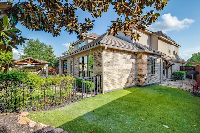 view of side of property with fence, a lawn, and brick siding