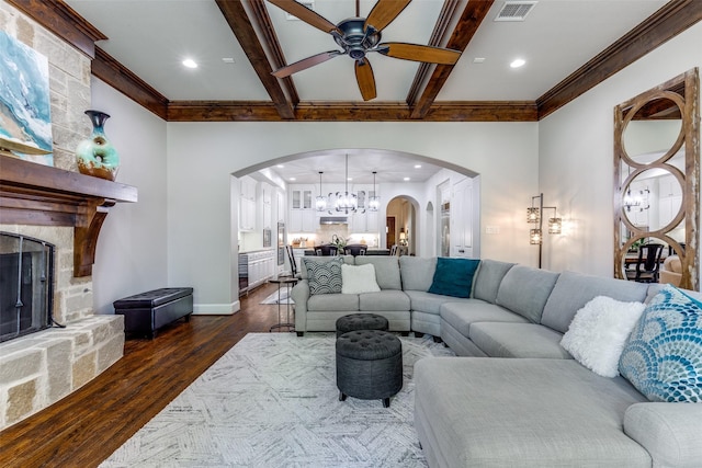 living room featuring a fireplace, arched walkways, dark wood finished floors, ceiling fan with notable chandelier, and baseboards