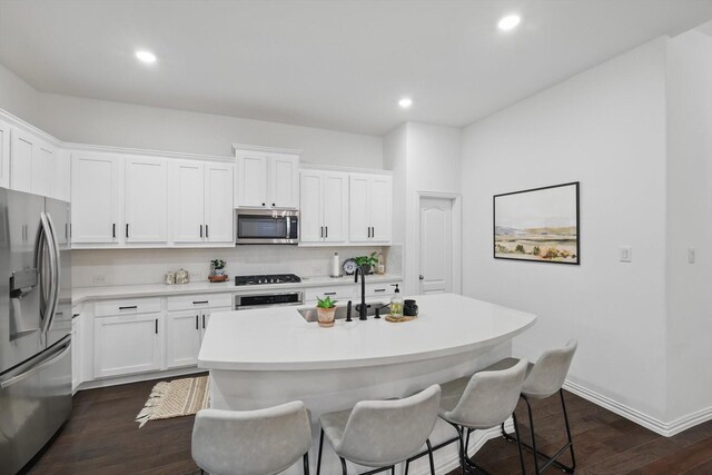 kitchen featuring dark wood-type flooring, a sink, a breakfast bar, and stainless steel appliances