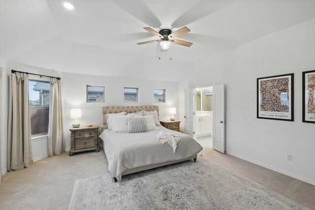 bedroom with light colored carpet, ensuite bath, a ceiling fan, baseboards, and vaulted ceiling