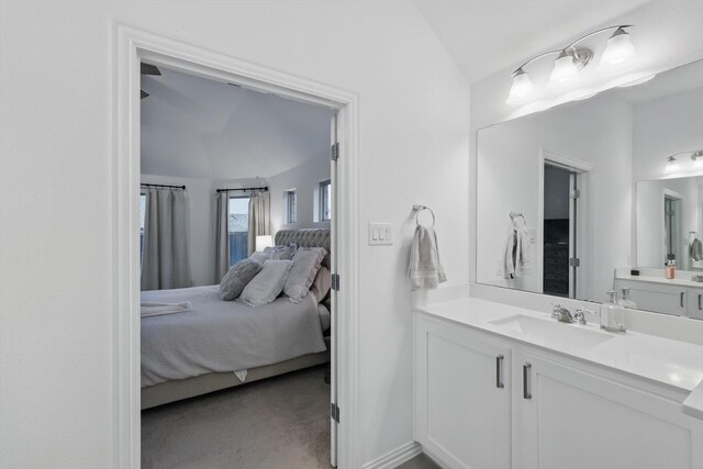 ensuite bathroom featuring vanity, vaulted ceiling, and connected bathroom