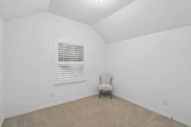 unfurnished room featuring baseboards, carpet flooring, and lofted ceiling
