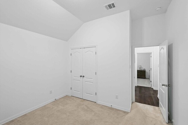 unfurnished bedroom with baseboards, visible vents, carpet, and lofted ceiling