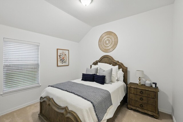 bedroom with baseboards, vaulted ceiling, and light carpet