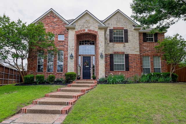 traditional-style house with fence, stone siding, brick siding, and a front yard