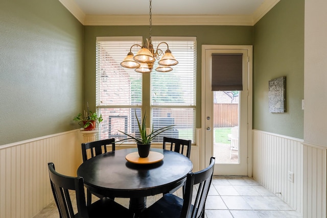 dining area featuring crown molding, a textured wall, a wainscoted wall, and a notable chandelier