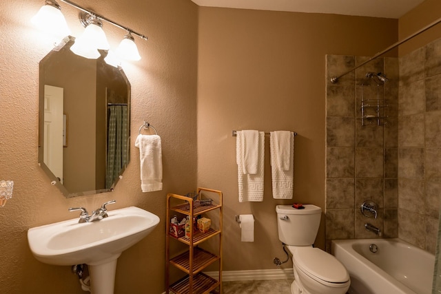 bathroom featuring tile patterned flooring, a sink, washtub / shower combination, and toilet