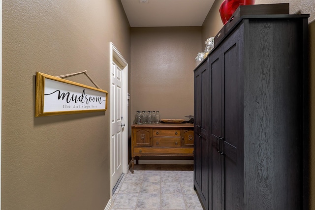 corridor with baseboards and a textured wall