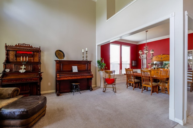 living area with baseboards, a notable chandelier, ornamental molding, and carpet