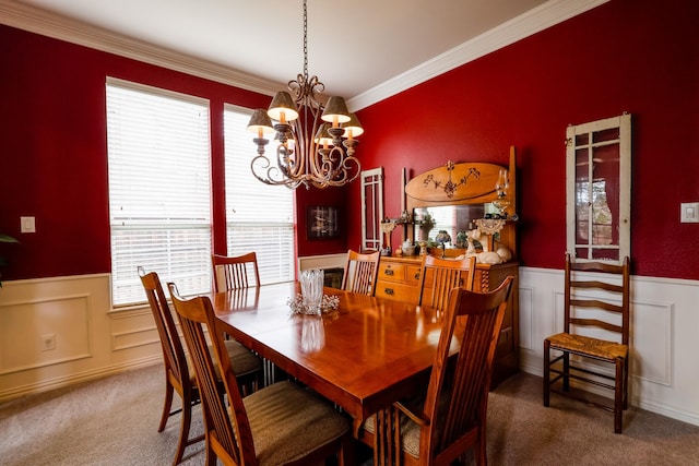 carpeted dining area with ornamental molding, wainscoting, and a notable chandelier