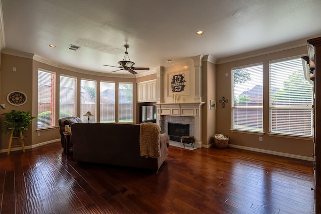 living area with ceiling fan, visible vents, a tile fireplace, baseboards, and ornamental molding