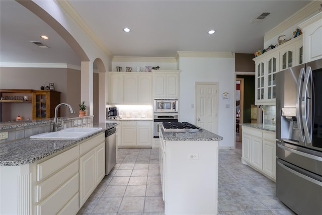 kitchen with a kitchen island, backsplash, appliances with stainless steel finishes, and a sink