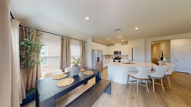 kitchen with white cabinets, appliances with stainless steel finishes, light wood-style floors, light countertops, and visible vents