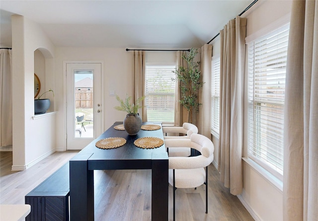 dining area featuring light wood-style floors, baseboards, and lofted ceiling