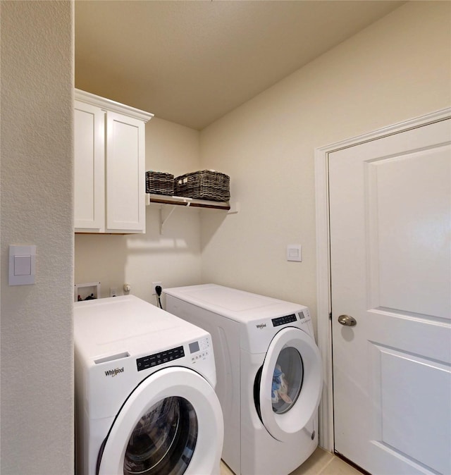 washroom featuring cabinet space and washer and clothes dryer
