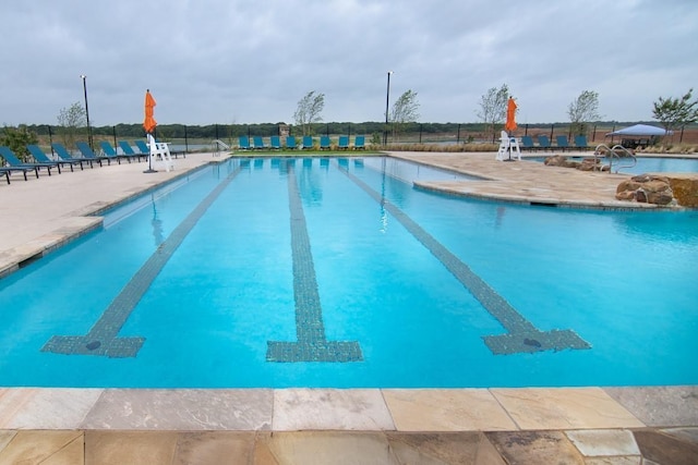 community pool featuring fence and a patio