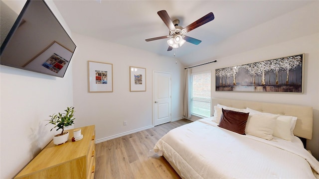 bedroom with baseboards, ceiling fan, light wood-style flooring, and lofted ceiling