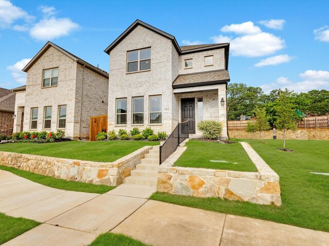 view of front of home with brick siding, fence, and a front yard