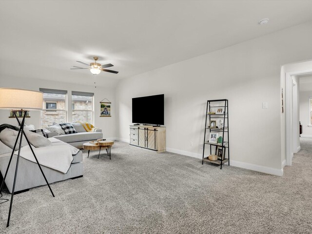 living room featuring baseboards, ceiling fan, and carpet