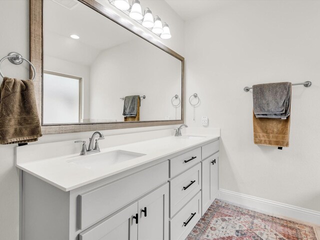 full bathroom with a sink, baseboards, and double vanity