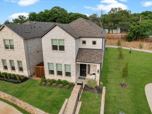 view of front of house featuring fence, a shingled roof, and a front yard