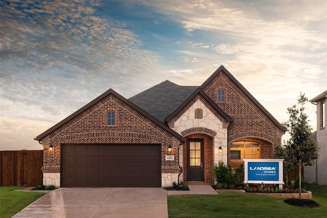 french provincial home featuring fence, a front yard, stone siding, brick siding, and driveway