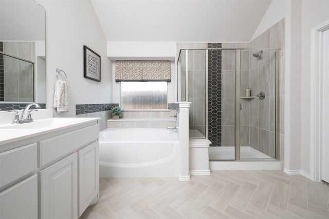 bathroom with vanity, a garden tub, lofted ceiling, and a stall shower