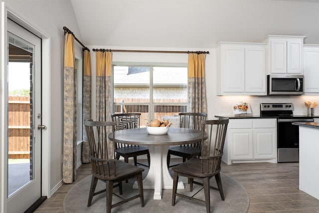 dining space featuring wood finished floors and lofted ceiling