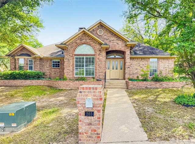 ranch-style house with a shingled roof and brick siding