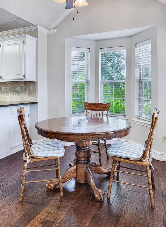 dining room with ornamental molding, dark wood finished floors, lofted ceiling, and a wealth of natural light