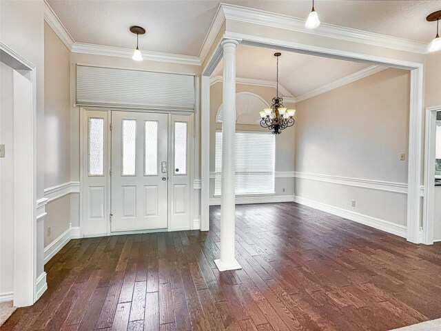 foyer entrance featuring dark wood-style flooring, ornate columns, an inviting chandelier, and a wealth of natural light