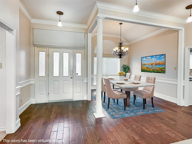 entrance foyer featuring dark wood-type flooring, decorative columns, crown molding, and an inviting chandelier