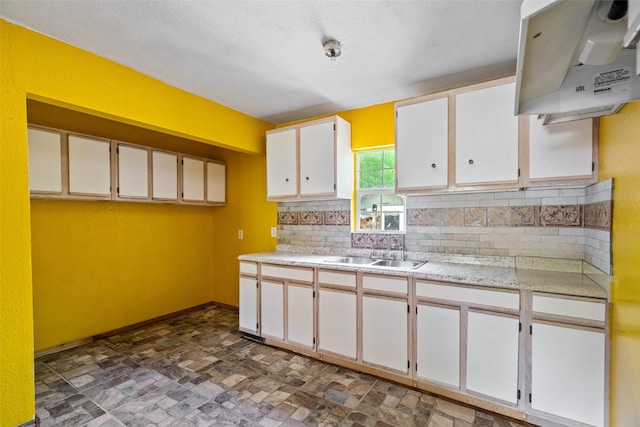kitchen with backsplash, range hood, a sink, light countertops, and white cabinets