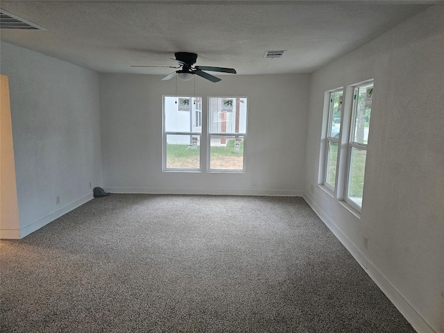 carpeted empty room with baseboards, visible vents, and ceiling fan