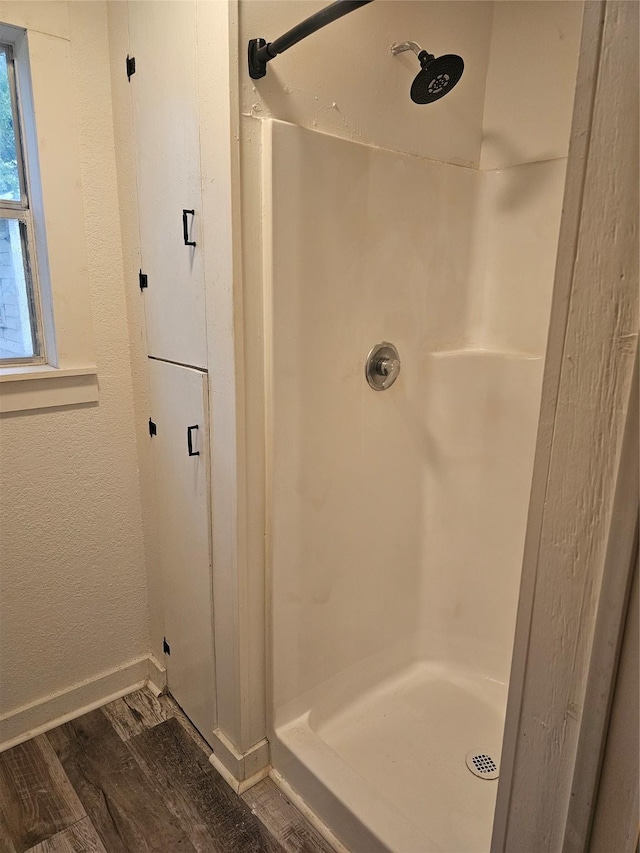 full bath featuring baseboards, wood finished floors, and a stall shower