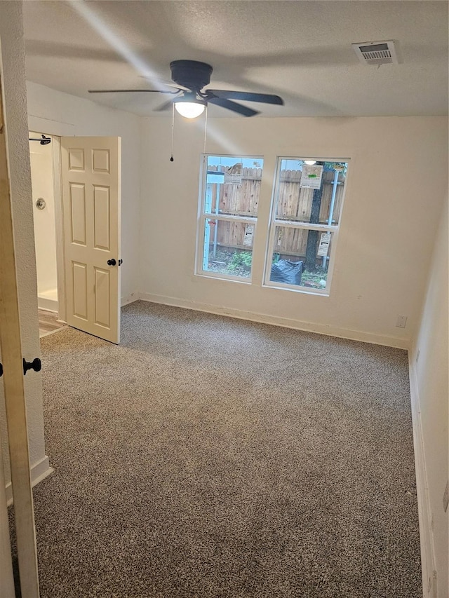 carpeted empty room with visible vents, baseboards, and ceiling fan