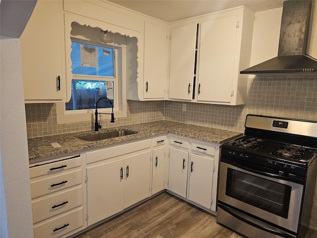 kitchen with gas range, wall chimney exhaust hood, white cabinets, a sink, and dark wood finished floors