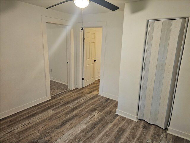 unfurnished bedroom with baseboards, a ceiling fan, and dark wood-type flooring